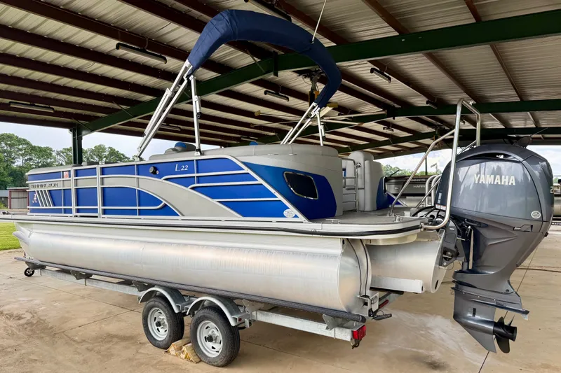 Slide: The Image of 2024 Bennington L22 pontoon boat with Yamaha engine on trailer in covered storage. - 2