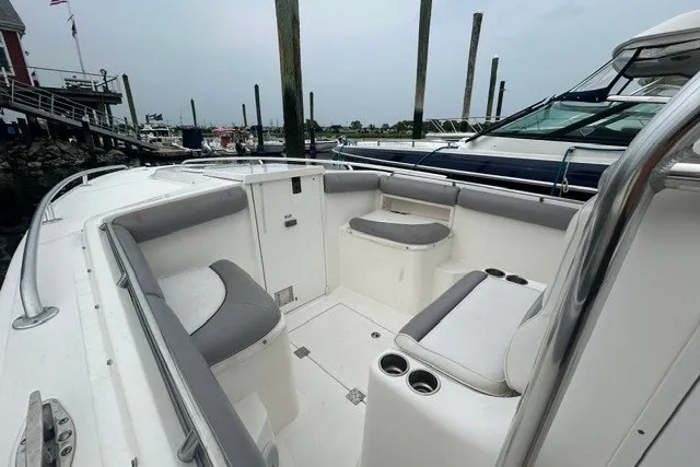 Slide: The Image of 2008 Jefferson Marlago 35 boat interior with cushioned seating and cup holders at a marina. - 6
