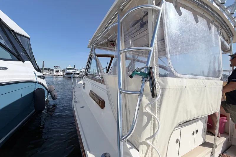 Slide: The Image of 2015 Fortier 30 boat docked at marina, clear sky, adjacent to another vessel. - 14