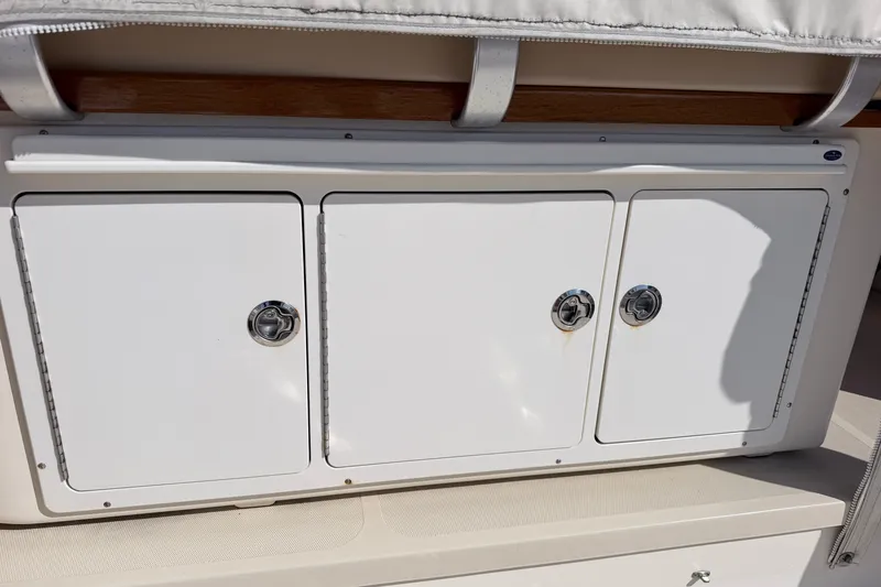 Slide: The Image of Storage compartments on a 2015 Fortier 30 boat, featuring sleek white doors and metal handles. - 13