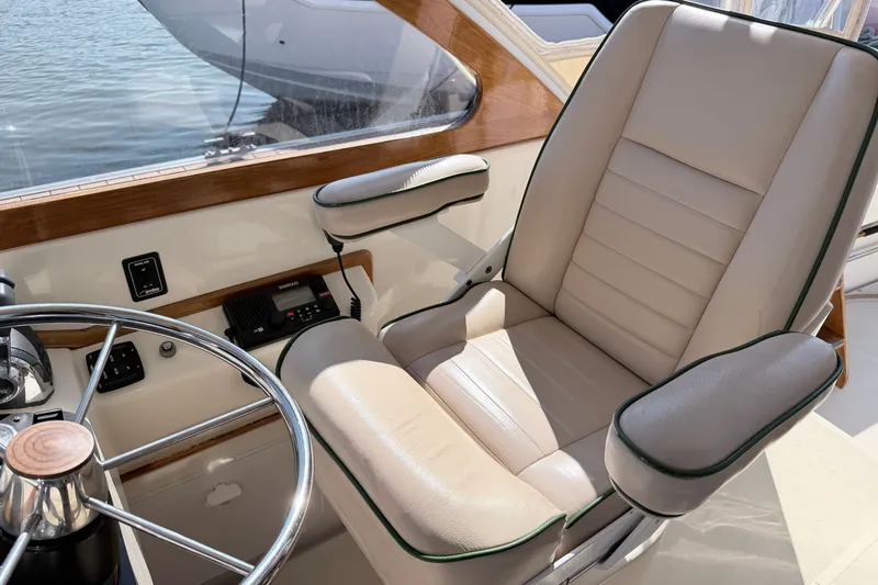 Slide: The Image of Captain's chair and steering wheel on a 2015 Fortier 30 boat, with beige upholstery. - 20