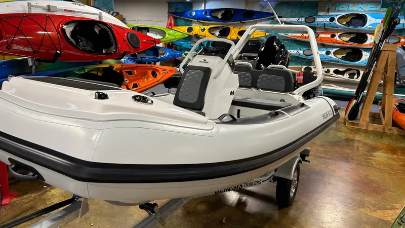 Slide: The Image of 2025 Highfield Sport 420 boat displayed indoors with colorful kayaks in the background. - 3