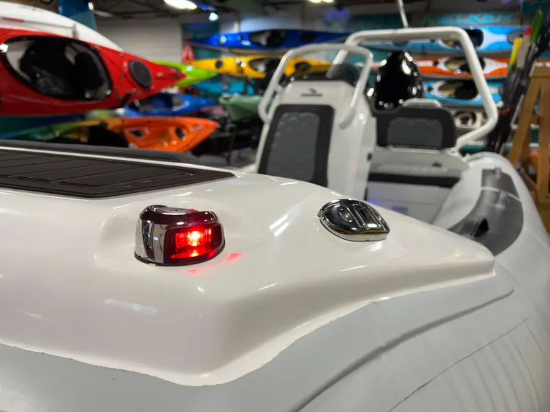 Slide: The Image of 2025 Highfield Sport 420 boat with red navigation light, surrounded by colorful kayaks. - 7