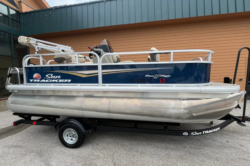 The Image of 2025 Sun Tracker Bass Buggy 16 XL Select pontoon boat on trailer, side view. - 0