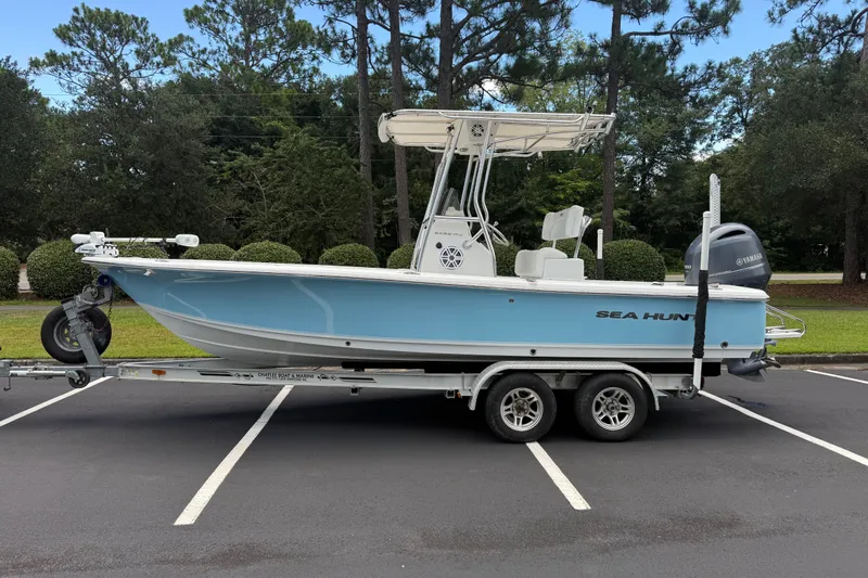 The Image of 2015 Sea Hunt BX22 Pro boat on trailer in parking lot, surrounded by trees. - 1