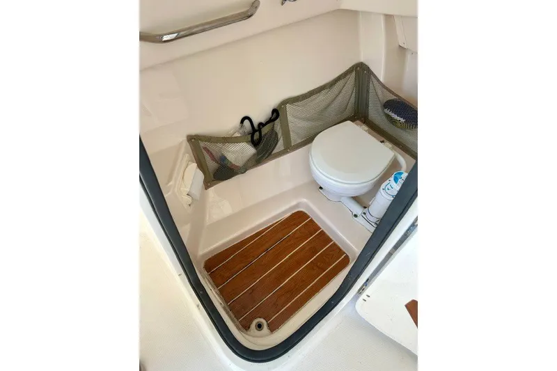 Slide: The Image of 2015 Grady-White Freedom 255 boat interior with compact marine toilet and wooden floor. - 5