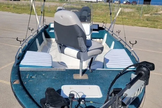 Slide: The Image of 1999 ProMaster 220 Bay boat with seating and fishing rod holders, parked outdoors. - 7
