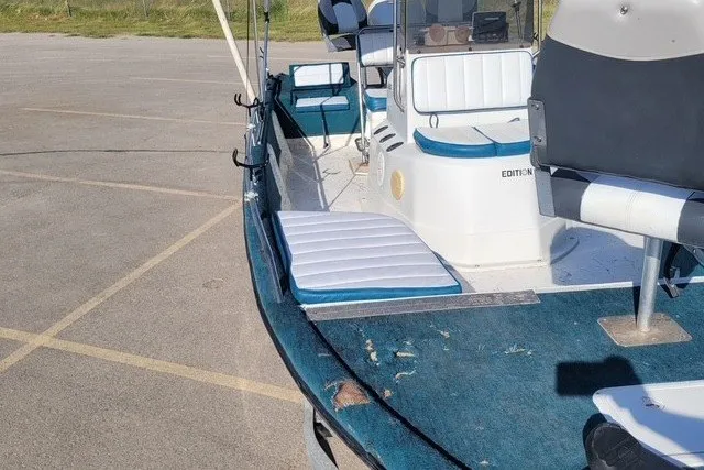 Slide: The Image of 1999 ProMaster 220 Bay boat with blue and white seating, parked on pavement. - 9