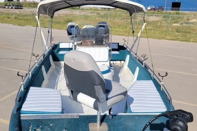 Slide: The Image of 1999 ProMaster 220 Bay boat with canopy, seating, and fishing rod holders in a parking lot. - 10