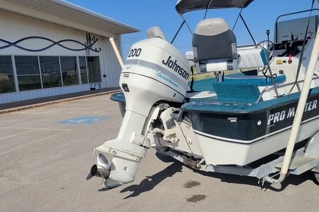 Slide: The Image of 1999 ProMaster 220 Bay boat with Johnson 200 outboard motor in parking lot. - 2