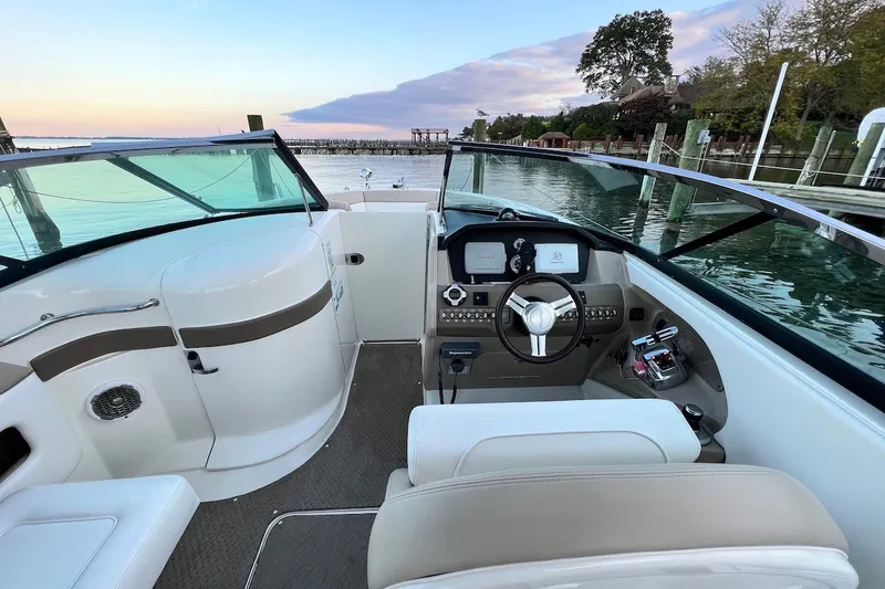 Slide: The Image of 2013 Sea Ray 300 SLX boat interior with steering wheel, dashboard, and waterfront view. - 3