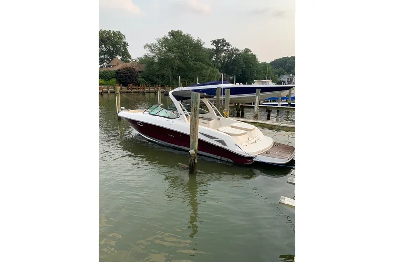 The Image of 2013 Sea Ray 300 SLX boat docked on calm water, surrounded by lush greenery. - 0