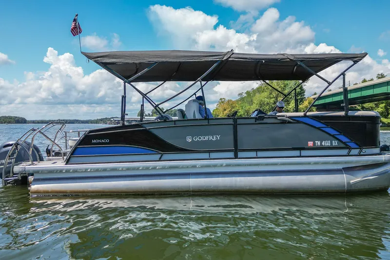 Slide: The Image of 2021 Godfrey Monaco 235 pontoon boat on a lake under a blue sky. - 4