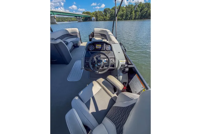 Slide: The Image of 2021 Godfrey Monaco 235 boat interior with steering wheel and seating on a calm river. - 34