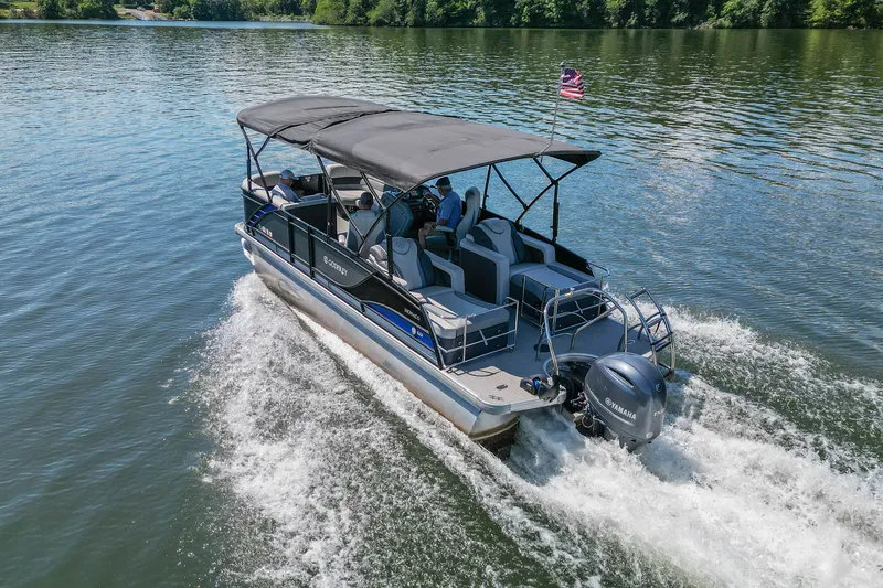 Slide: The Image of 2021 Godfrey Monaco 235 pontoon boat cruising on a serene lake. - 12