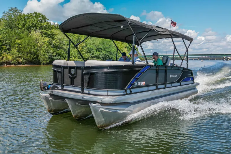 The Image of 2021 Godfrey Monaco 235 pontoon boat cruising on a scenic lake under a clear blue sky. - 1