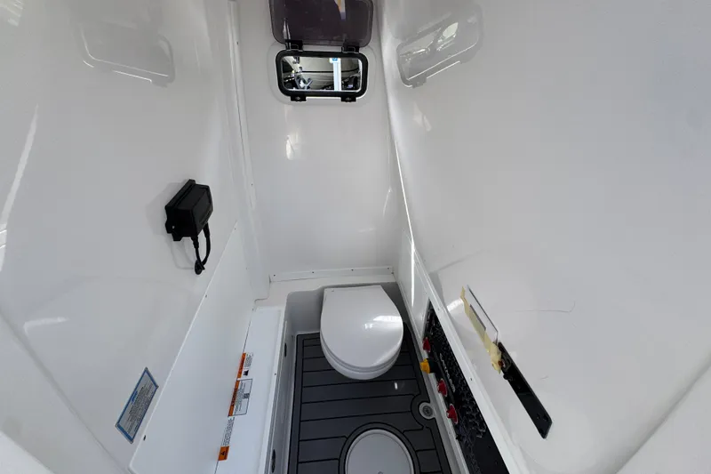 Slide: The Image of Interior of 2027 Caymas 291 boat, featuring a compact, modern bathroom with toilet and control panel. - 27