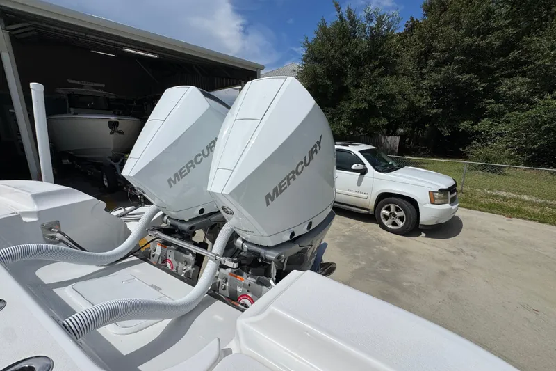 Slide: The Image of Twin Mercury engines on a 2027 Caymas 291 boat, parked near a white SUV. - 43
