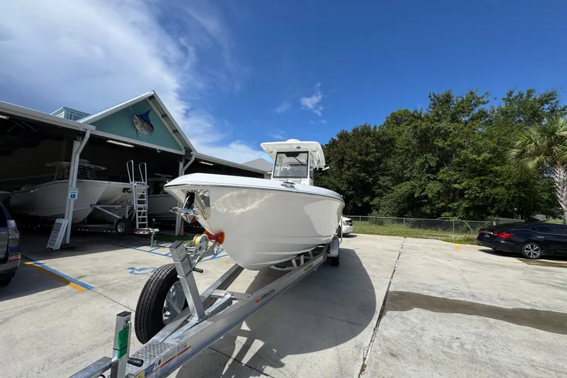 Slide: The Image of 2027 Caymas 291 boat on trailer, parked outside a marina under a clear blue sky. - 5