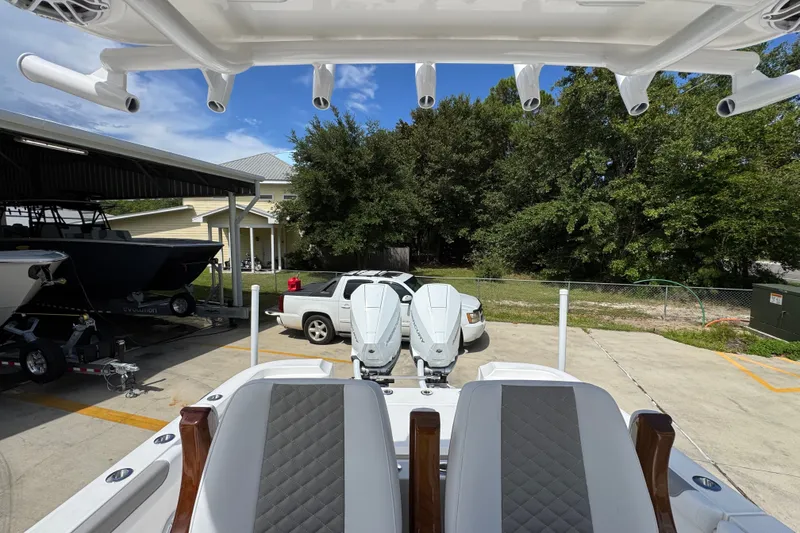 Slide: The Image of 2027 Caymas 291 boat with dual engines, parked near a house and trees. - 30