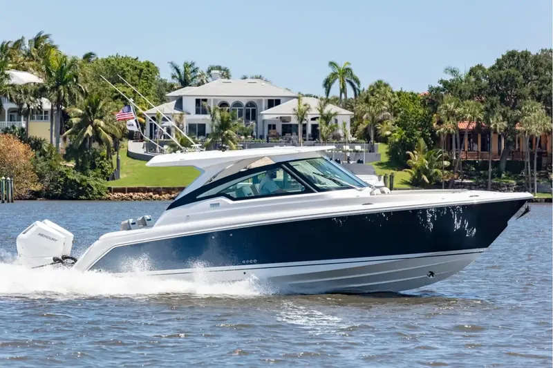 The Image of 2027 Tiara Yachts 34 LX cruising on a scenic waterway with luxury homes in the background. - 0