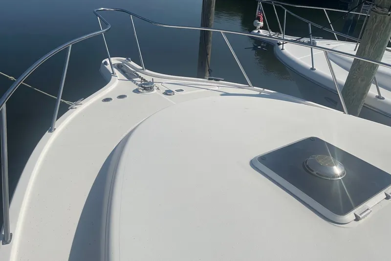 Slide: The Image of 1997 Pursuit 3400 Express boat deck with railing and hatch, docked on calm water. - 2