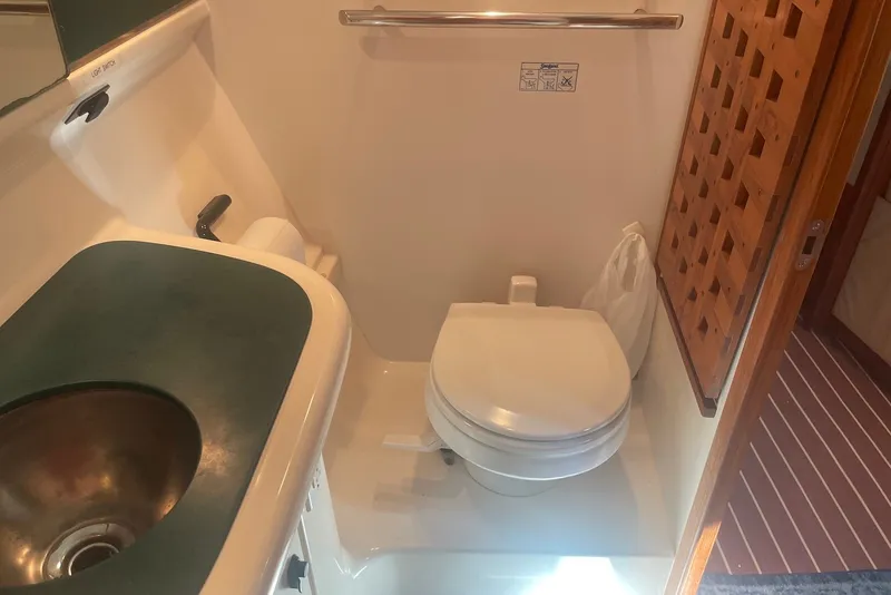 Slide: The Image of Bathroom interior of a 1997 Pursuit 3400 Express boat, featuring a toilet and sink. - 22