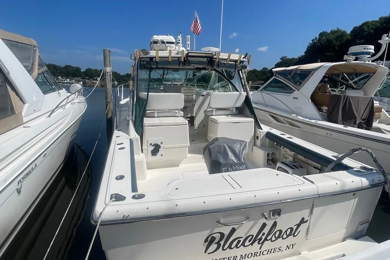Slide: The Image of 1997 Pursuit 3400 Express boat docked, featuring spacious deck and seating, named "Blackfoot." - 4