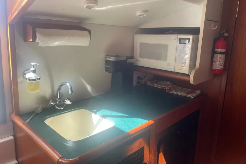 Slide: The Image of Compact kitchen area in a 1997 Pursuit 3400 Express boat with sink, microwave, and coffee maker. - 20