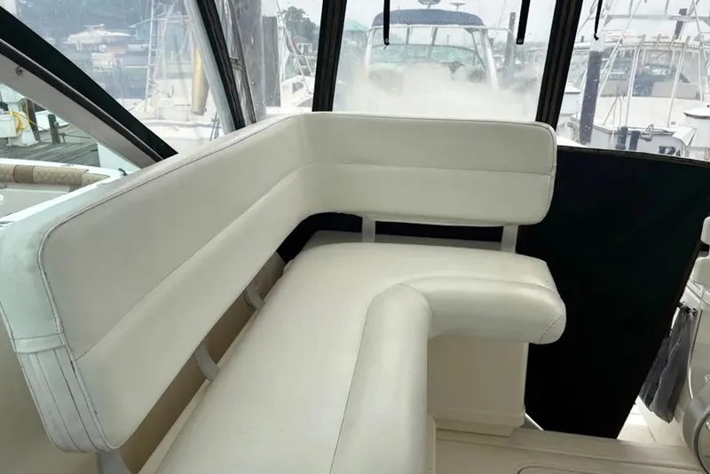 Slide: The Image of Interior seating of a 1997 Pursuit 3400 Express boat, featuring white cushioned benches. - 8