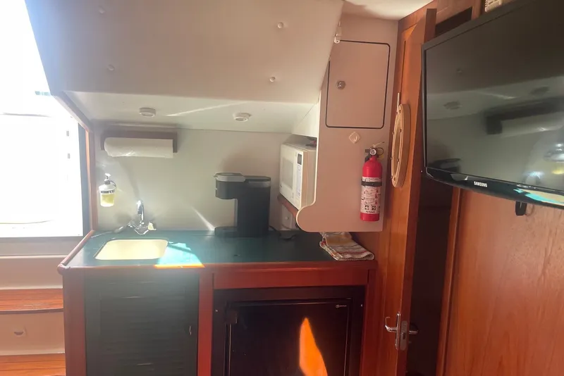 Slide: The Image of Interior of 1997 Pursuit 3400 Express boat featuring kitchenette with sink, microwave, and TV. - 16