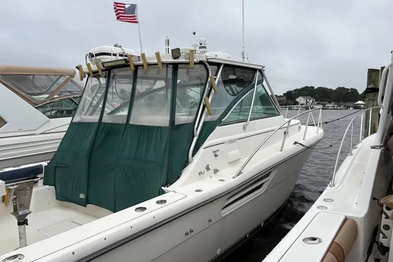 Slide: The Image of 1997 Pursuit 3400 Express boat docked, featuring green canopy and American flag. - 1