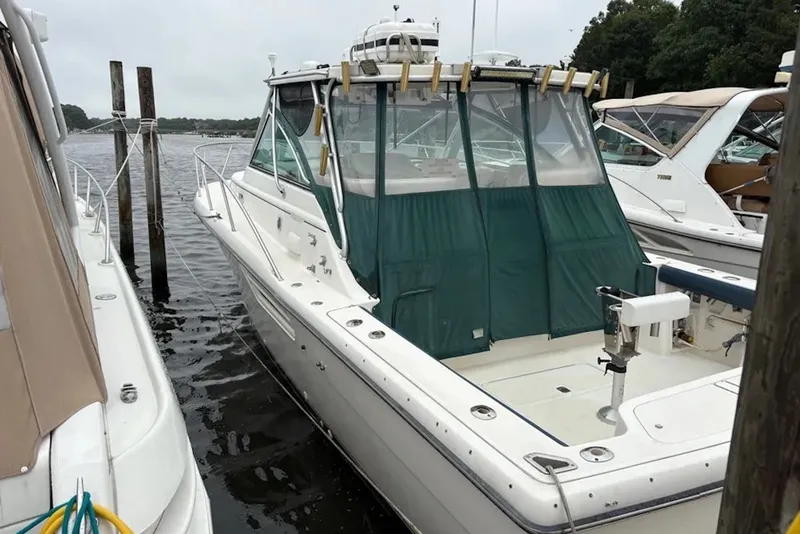 The Image of 1997 Pursuit 3400 Express boat docked at marina, featuring green canvas cover. - 0