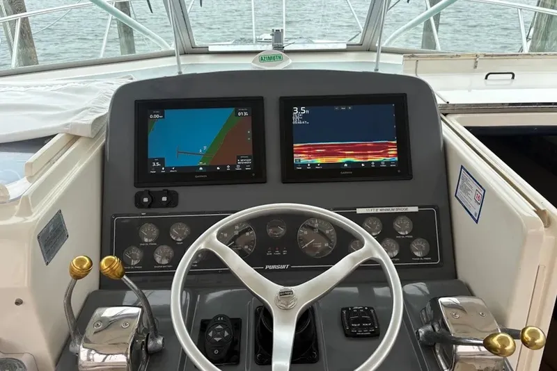 Slide: The Image of Helm of 1997 Pursuit 3400 Express boat with dual navigation screens and controls. - 11