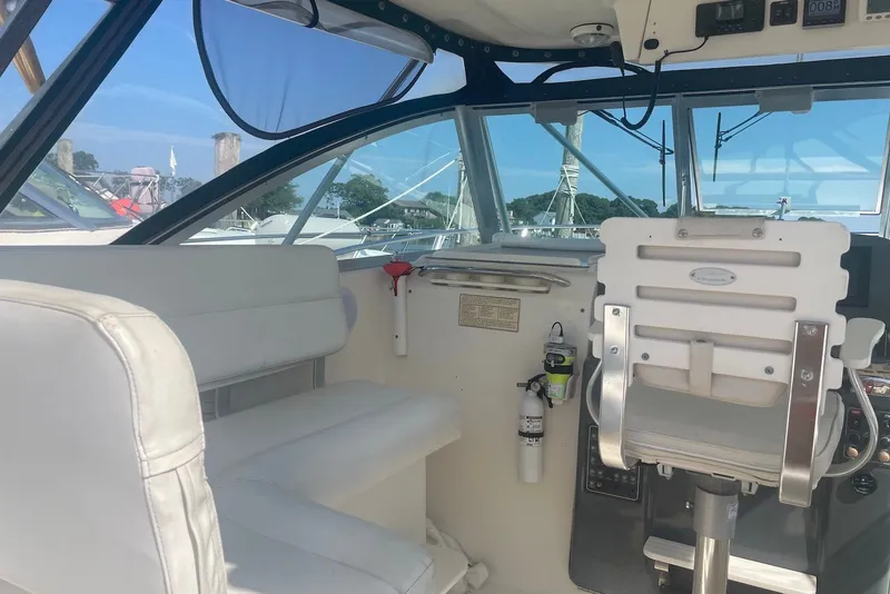 Slide: The Image of Interior of a 1997 Pursuit 3400 Express boat with white seating and control panel. - 12