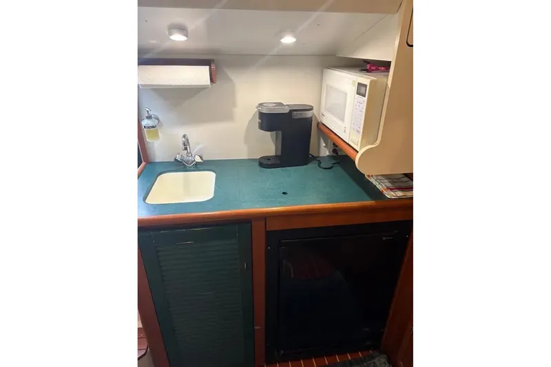 Slide: The Image of 1997 Pursuit 3400 Express boat kitchenette with sink, microwave, and coffee maker. - 18