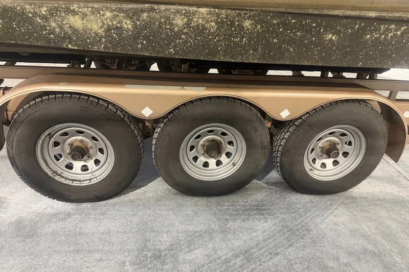 Slide: The Image of Triple-axle trailer for 1997 Cruisers Yachts 337 Esprit, showcasing sturdy wheels and fenders. - 29