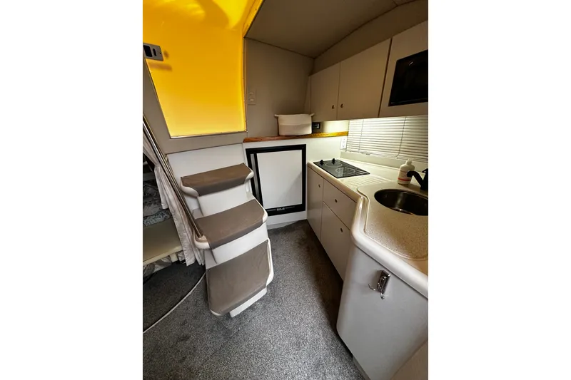 Slide: The Image of Interior of 1997 Cruisers Yachts 337 Esprit, featuring compact kitchen and stairs. - 8