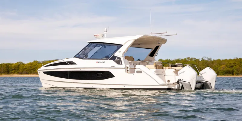 Slide: The Image of 2021 Aquila 36 Sport boat cruising on a calm lake with scenic background. - 1