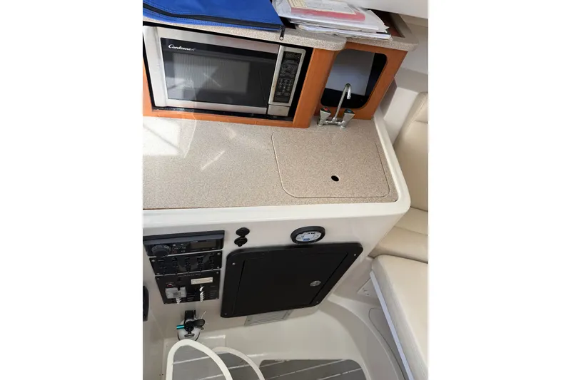 Slide: The Image of 2014 Sailfish 270 WAC boat interior with microwave, sink, and control panel. - 19