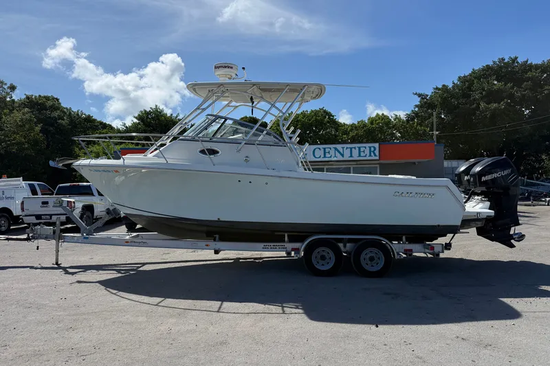 The Image of 2014 Sailfish 270 WAC boat on trailer, parked outdoors near service center. - 1