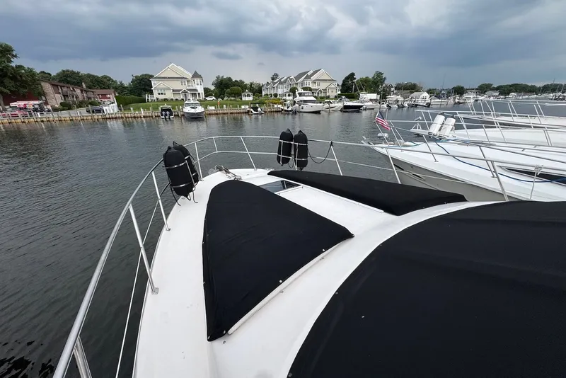 Slide: The Image of 1998 Sea Ray 420 Aft Cabin yacht docked in a marina with waterfront homes. - 10