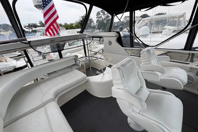 Slide: The Image of 1998 Sea Ray 420 Aft Cabin yacht interior with white seating and American flag. - 8