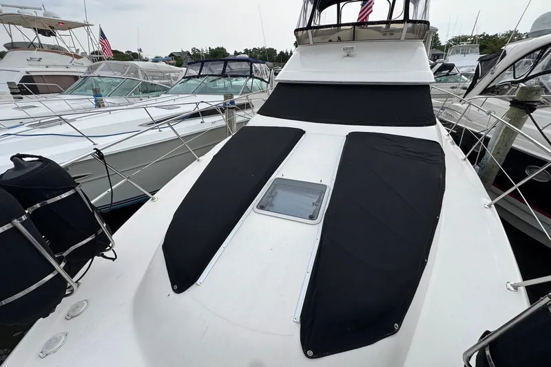 Slide: The Image of 1998 Sea Ray 420 Aft Cabin yacht docked, featuring black sun pads and a hatch. - 12