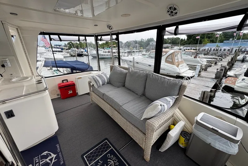 Slide: The Image of 1998 Sea Ray 420 Aft Cabin interior with wicker sofa, marina view, and docked boats. - 4