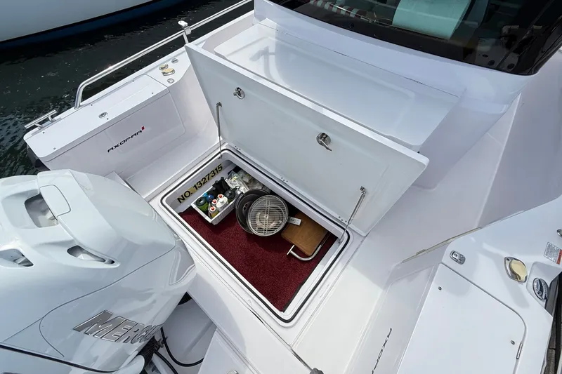 Slide: The Image of 2022 Axopar 28 Cabin boat storage compartment with supplies and Mercury engine. - 11