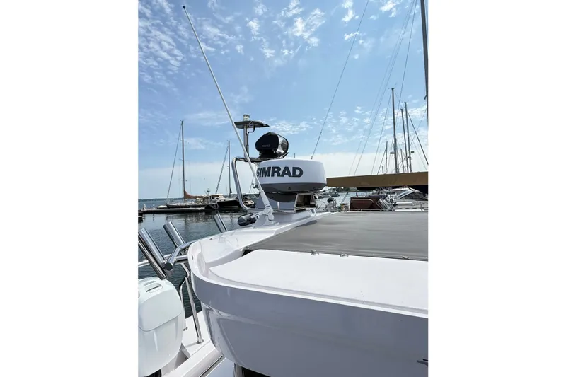 Slide: The Image of 2022 Axopar 28 Cabin boat with Simrad radar, docked at a marina under blue sky. - 38