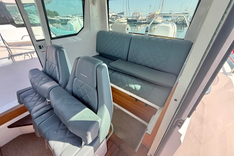 Slide: The Image of Interior of 2022 Axopar 28 Cabin boat with plush seating and marina view. - 23