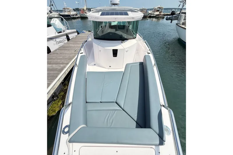 Slide: The Image of 2022 Axopar 28 Cabin boat with sleek seating, docked at a marina. - 32