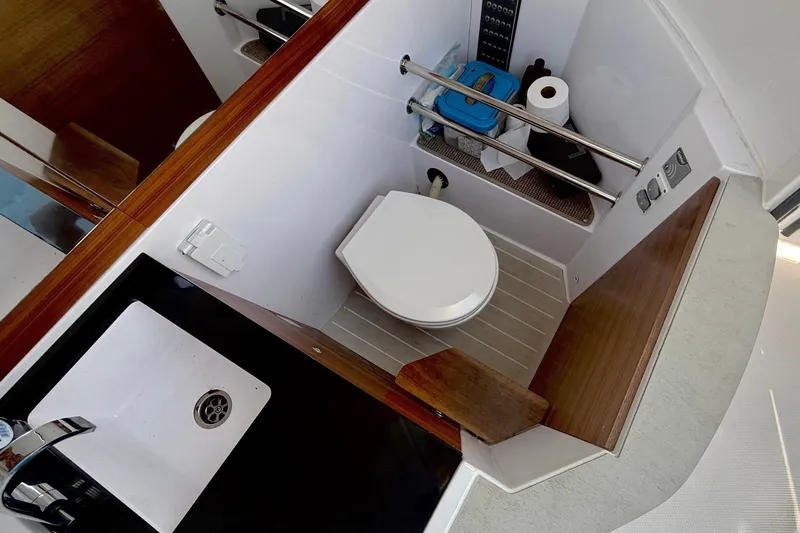Slide: The Image of 2022 Axopar 28 Cabin bathroom with toilet, sink, and storage shelves. - 35